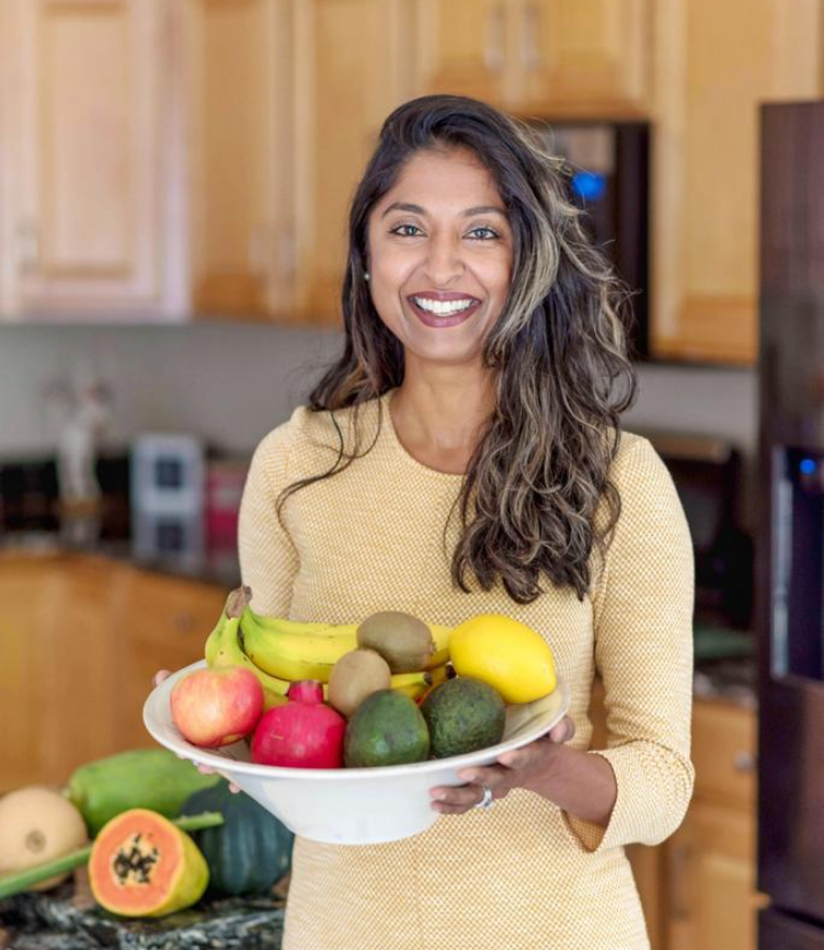 Raman Magay holding a bowl of fresh produce in a kitchen